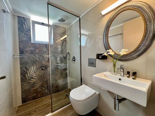 ein Badezimmer mit einem WC, einem Waschbecken und einem Spiegel in der Unterkunft Maria Hotel Sisi in Sisi