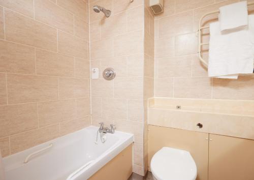 a bathroom with a tub and a toilet and a sink at Farmhouse Innlodge by Greene King Inns in Portsmouth