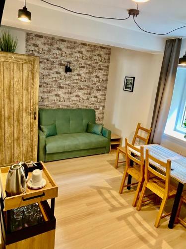a living room with a green couch and a table at Old Tree Home & Restaurant in Oświęcim