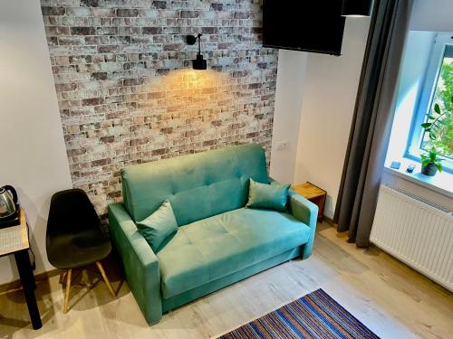 a green couch in a living room with a brick wall at Old Tree Home & Restaurant in Oświęcim