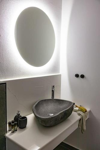 a bathroom with a sink with a round mirror at Beachfront Villa Crystalia in Lachania