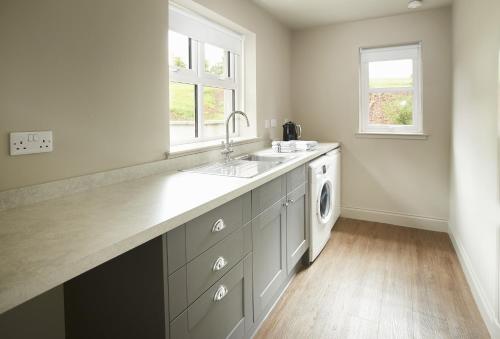 a kitchen with a sink and a washing machine at Netherwood Lodge in Dumfries