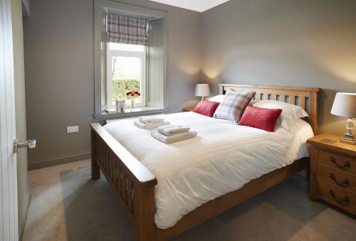 a bedroom with a large bed with red pillows and a window at Netherwood Lodge in Dumfries