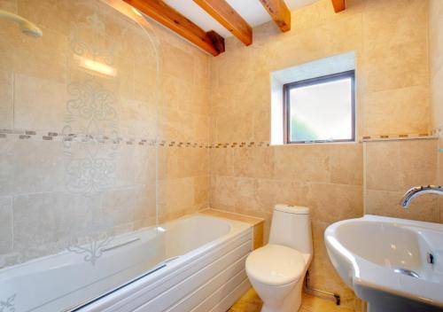 a bathroom with a tub and a toilet and a sink at Swallow Cottage in Haverfordwest