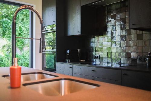 eine Küche mit einem Waschbecken und einem Fenster in der Unterkunft Gasthuis Veurne in Veurne