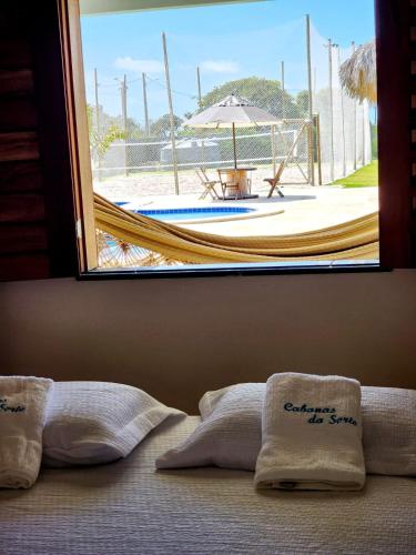 ein Bett mit Fenster und Blick auf einen Pool in der Unterkunft Cabanas da Sorte in Fortim