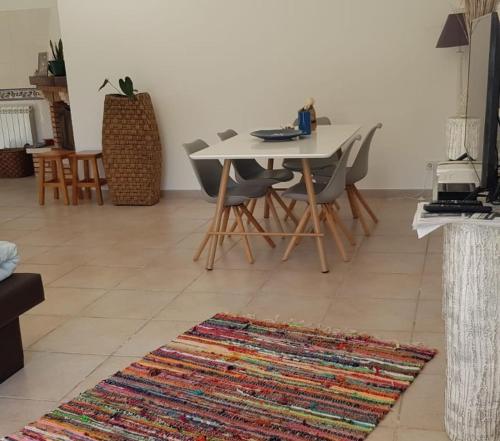 ein Wohnzimmer mit einem Tisch, Stühlen und einem Teppich in der Unterkunft Casa do Espinheiro in São Mamede