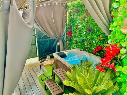 a balcony with a tub in a garden with flowers at La lover’s jungle in Pont-sur-Yonne