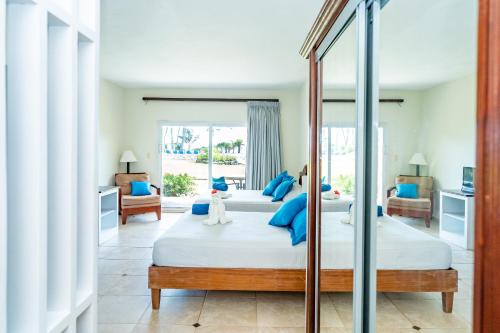 a bedroom with two beds with blue pillows and a mirror at Agualina Kite Hotel Oceanfront Apartments in Cabarete