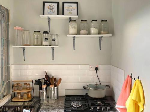 a kitchen with a stove and shelves with jars at Kivulini House - close to the beach in Dar es Salaam