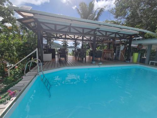 una piscina con pergolato, tavolo e sedie di Ocean View Apartment a Anse Possession