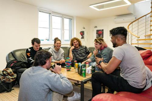 een groep mensen die rond een salontafel zitten bij Wild Elephants Hostel in Bratislava