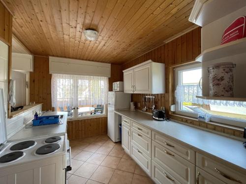 a kitchen with white appliances and a wooden ceiling at Gemütlicher Bungalow an der Mecklenburgischen Seenplatte in Jabel