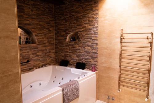 a bath tub in a bathroom with a brick wall at Apartamentos Ohana in Jadraque