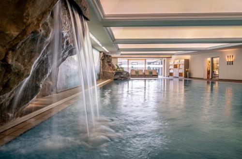 a swimming pool with a waterfall in a hotel room at Hotel Franks in Oberstdorf