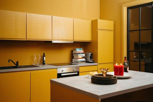 a kitchen with yellow cabinets and a counter with a candle at Laila Penthouse in Antwerp
