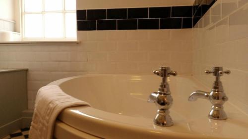 a bath tub with two faucets in a bathroom at Kings Arms Hotel in Bicester