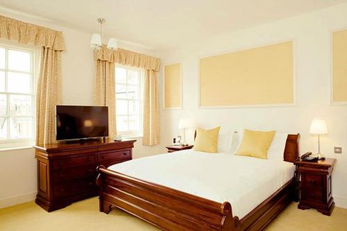 a bedroom with a bed and a flat screen tv at Kings Arms Hotel in Bicester