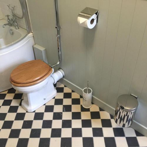 a bathroom with a toilet with a shower and a checkered floor at Kings Arms Hotel in Bicester