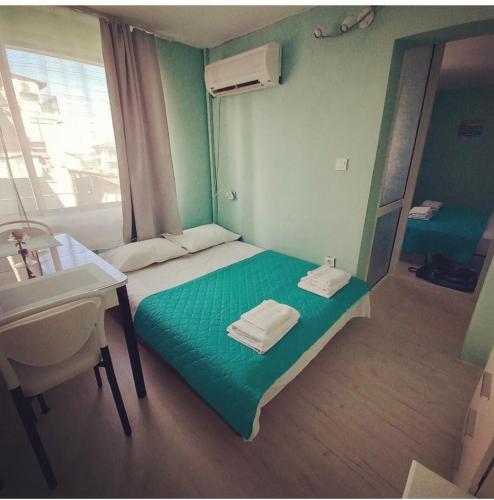 a small room with a green bed and a sink at Апартамент Холи in Sozopol