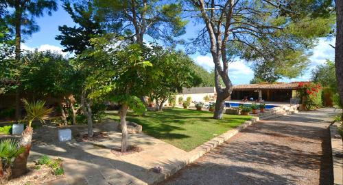 un jardín con árboles y una casa con un edificio en Villa Cas Cosinet by PriorityVillas, en Consell