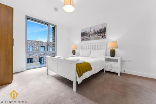 Dormitorio blanco con cama y ventana grande en Exclusive 3 bed 3bath Penthouse near Canary Wharf en Londres