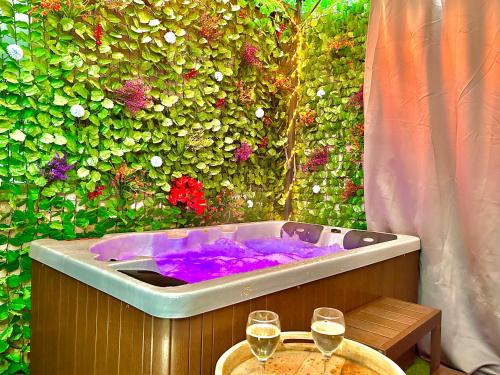 a bath tub with two glasses of wine on a table at La lover’s jungle in Pont-sur-Yonne