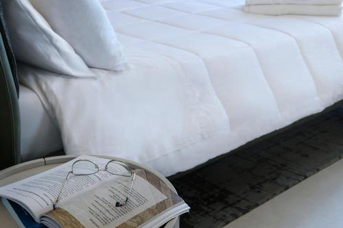 a bed with a book and glasses on a table at Bed&Belvedere in Otranto