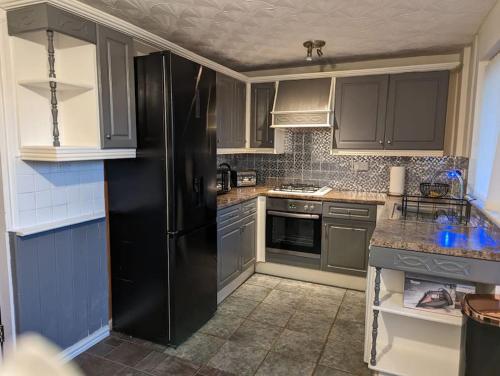 a kitchen with a black refrigerator and gray cabinets at Home away from home in Leigh