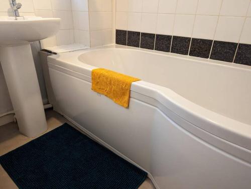 a white bath tub with a yellow towel on it at Home away from home in Leigh