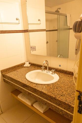 a bathroom counter with a sink and a mirror at SJ Tour - San Juan Foz do Iguaçu in Foz do Iguaçu