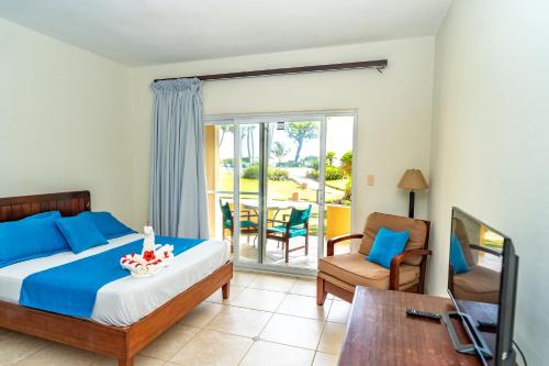 a bedroom with a bed and a chair and a balcony at Agualina Kite Hotel Oceanfront Apartments in Cabarete