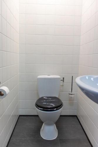 een badkamer met een toilet met een zwarte stoel en een wastafel bij Bed and Breakfast Harvey suite in Delden