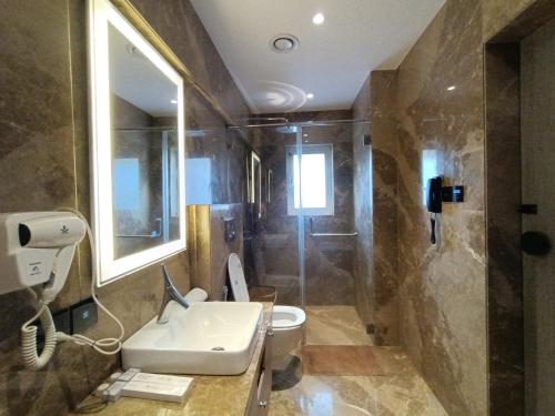 a bathroom with a toilet and a sink and a shower at Hotel Highway Inn Andheri East in Mumbai
