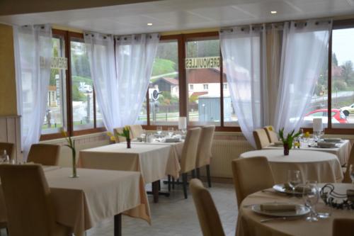 a restaurant with white tables and chairs and windows at Hotel Du Pont in La GrandʼCombe-Châteleu