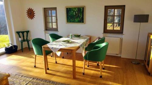 a dining room with a table and green chairs at An der Weinstraße - Idyllisches Ferienhäuschen im Naturparadies umgeben von Wiesen & Wäldern! in Zgornja Kungota