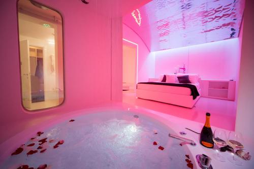 フィデンツァにあるDealuna Motelのバスタブ、ベッド、ピンクの照明が備わる客室です。
