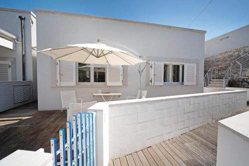 un patio con ombrellone, tavolo e sedie di WePuglia - Residence CalaPaura a Polignano a Mare