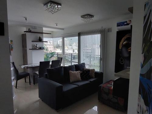a living room with a black couch and a table at Edificio Leonardo 6to piso in Villa Carlos Paz