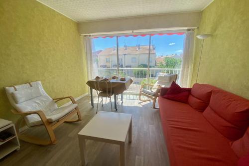 un salon avec un canapé rouge et une table dans l'établissement LES AIGRETTES - Studio proche de la plage, au Grau-du-Roi