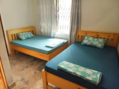 2 camas individuales en una habitación con ventana en Tulivu House -2bedroom vacation home close to the beach en Dar es Salaam