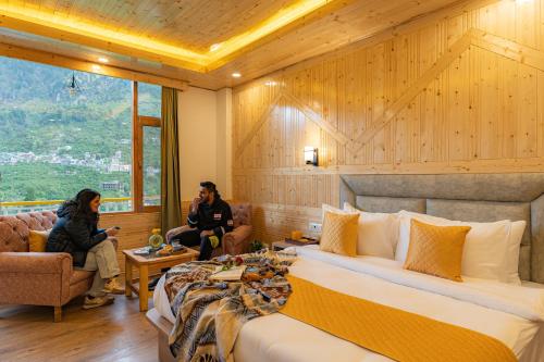 two people sitting in a hotel room with a bed at ArtBuzz Manali in Manāli