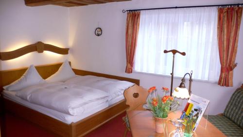 a bedroom with a bed and a table with flowers at Landhotel Quirle-Häusl in Waltersdorf