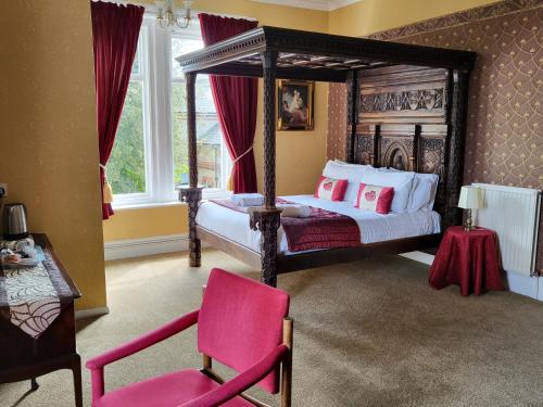 a bedroom with a canopy bed and a pink chair at Eastmount Hall Hotel in Shanklin
