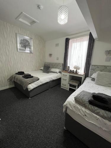 a bedroom with two beds and a desk and a window at The Carlton in Blackpool