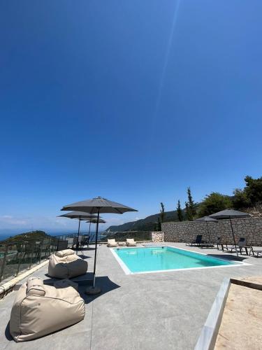 a swimming pool with umbrellas and chairs next to a pool at MELIKIRON LUXURY APARTMENTS in Agios Nikitas