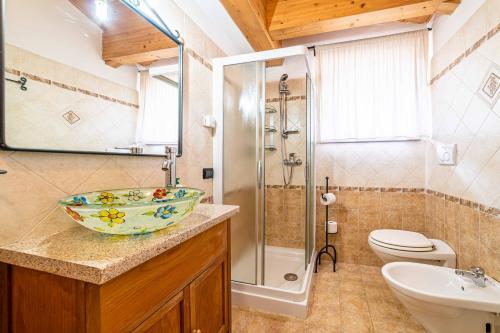 a bathroom with a sink and a shower with a bowl at Appartamento Dolomiti Alleghe in Alleghe