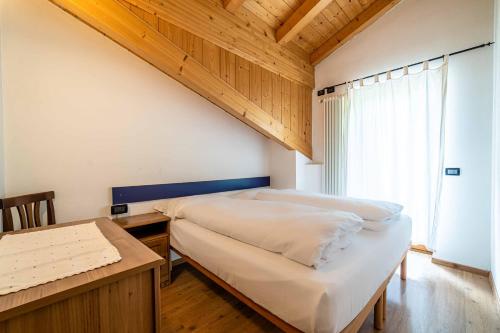 a bedroom with a bed and a desk and a window at Appartamento Dolomiti Alleghe in Alleghe