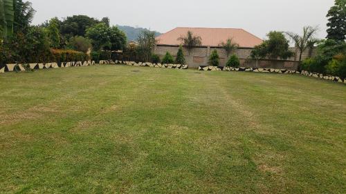 a large grassy yard with a fence in the background at Alice Gardens & Campsite in Entebbe