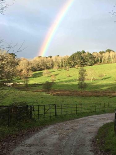 a rainbow over a field with a dirt road at Historic school room in Helston